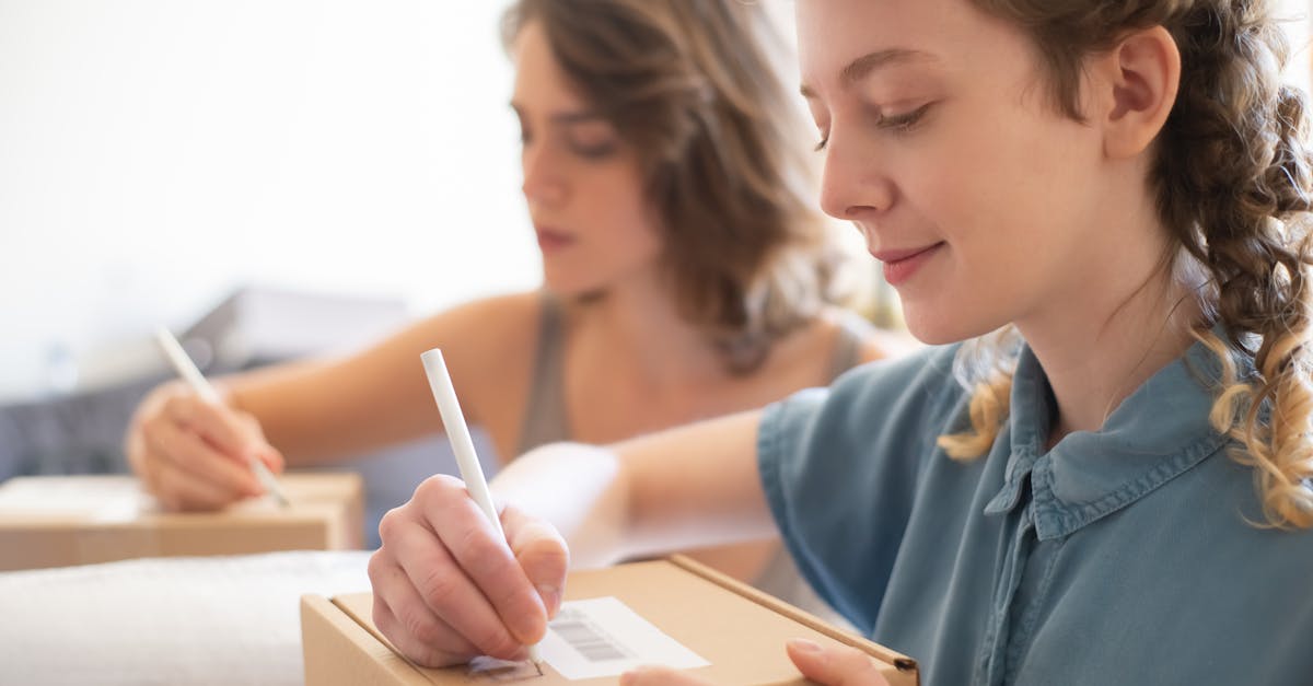 Two women packing boxes for an online store, focusing on barcode and labeling processes.